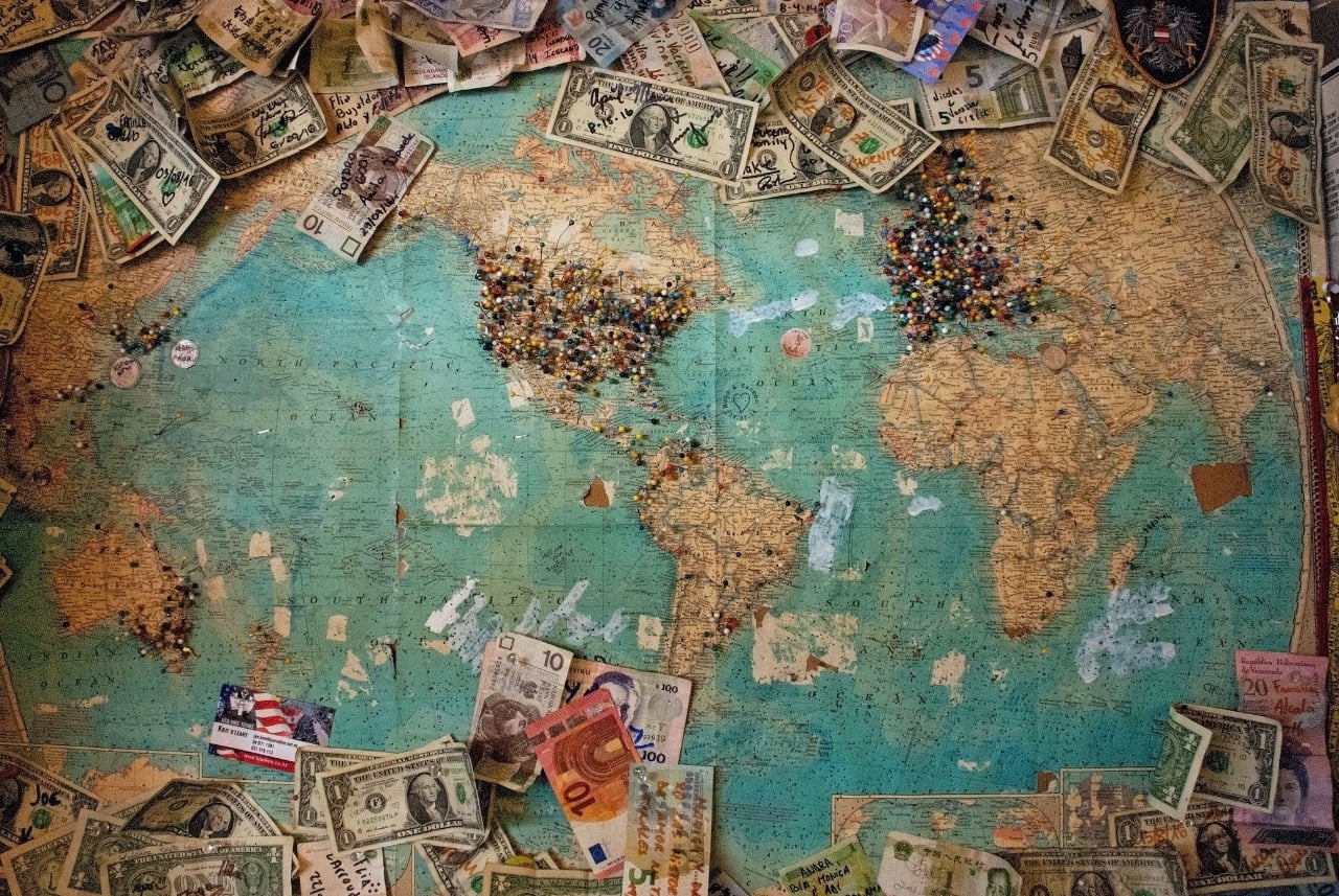 A picture of Money from all over the world upon a world map.