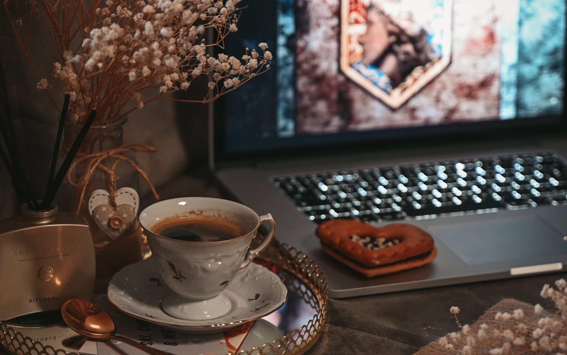 A picture showing a laptop which can be used to create a budget and cookies and tea next to it.