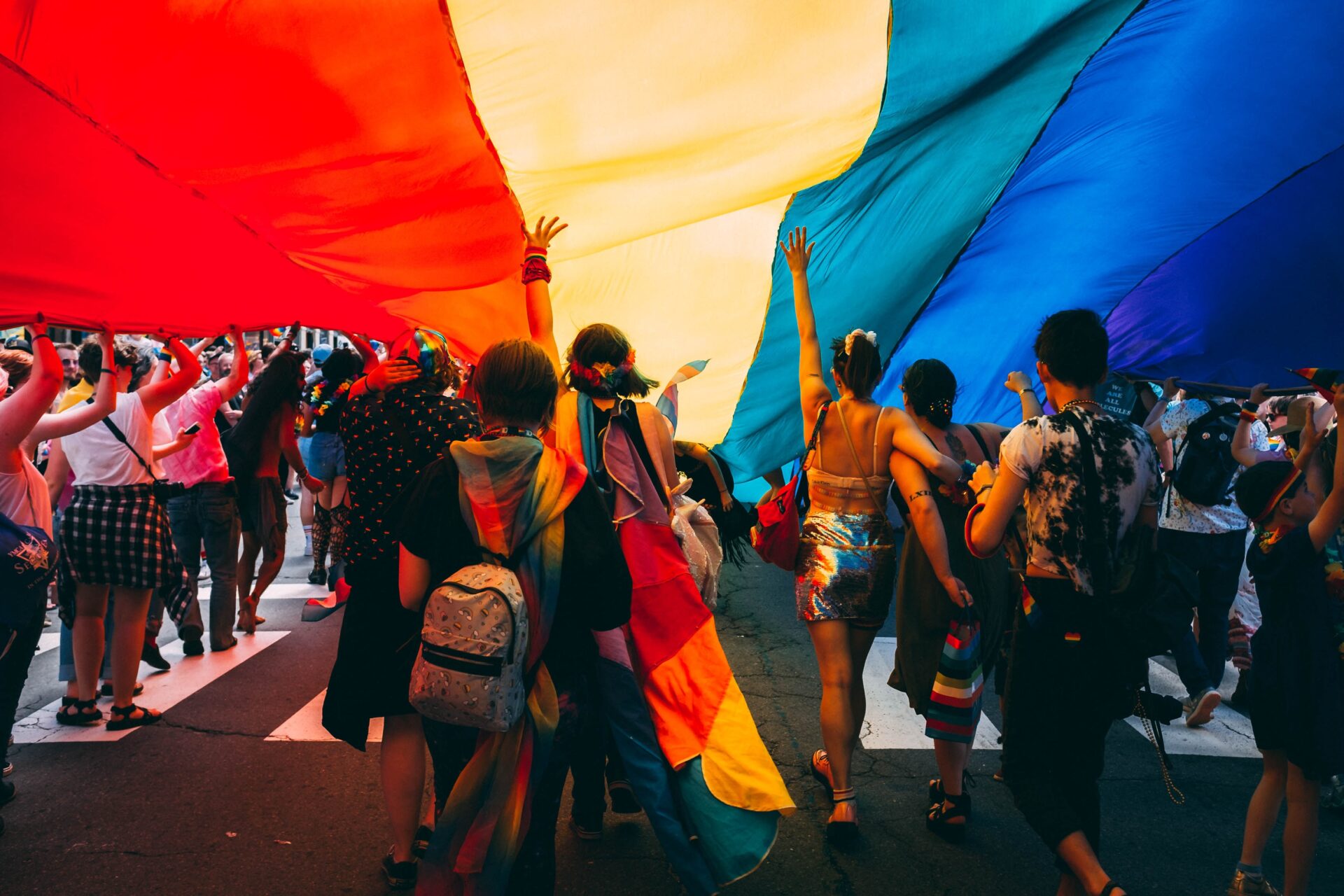 A picture of LGBTQIA+ members under a rainbow flag.