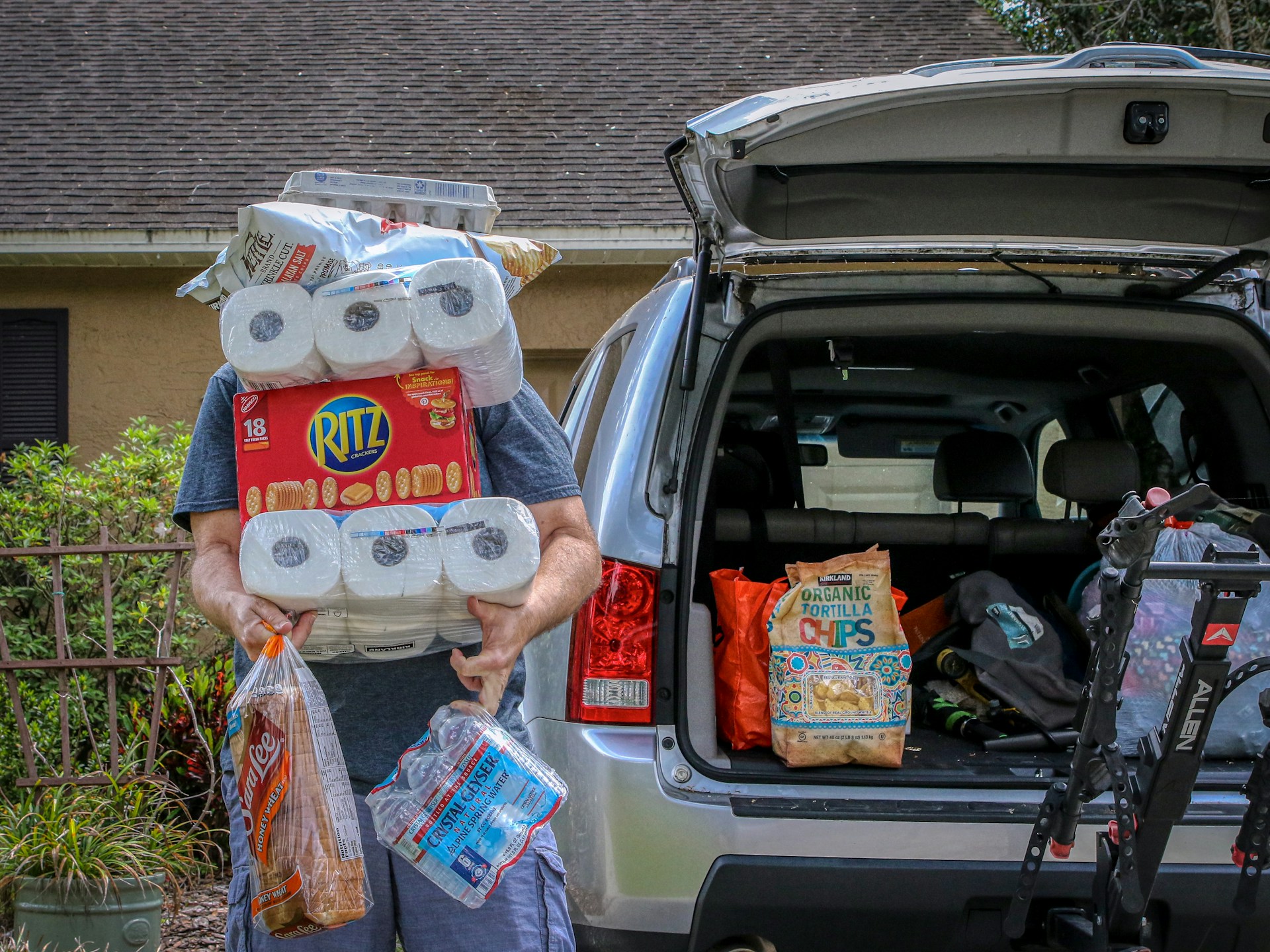 Person holding toilet paper outside their car trunk.