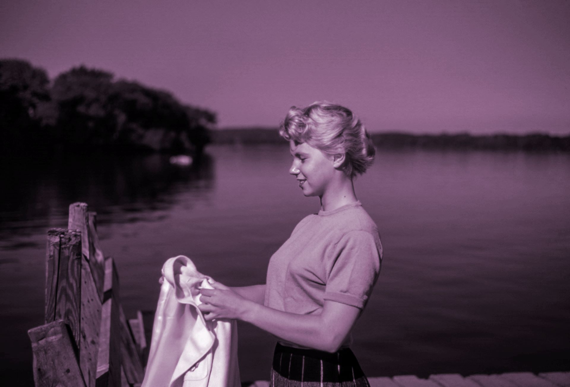 A picture of a woman holding a piece of cloth near a water body